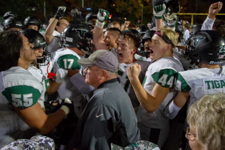 Players surround Coach Ruecker to celebrate their victory over West Linn. Ruecker, who has been a head coach for 42 years, 10 at Tigard, announced his retirement this week.