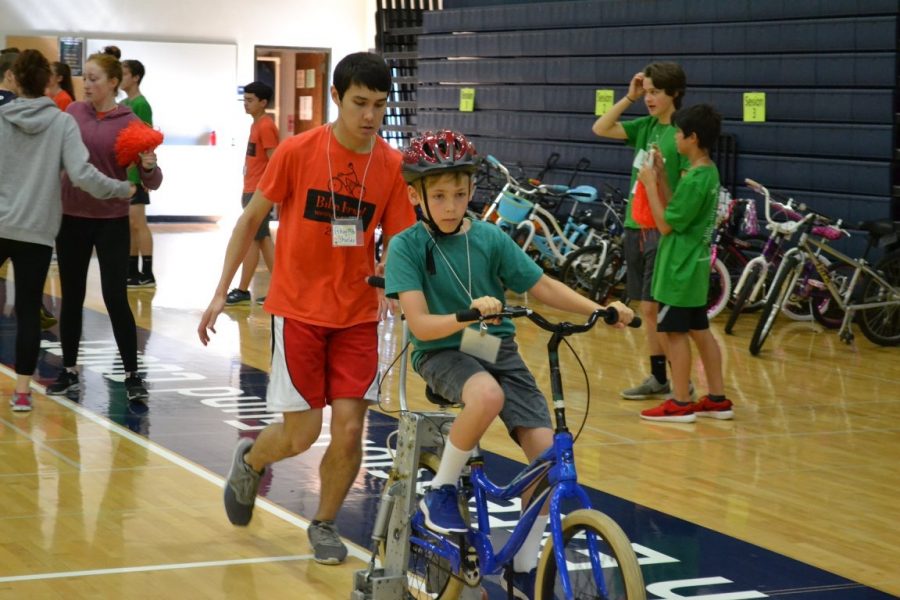 Ethan Shields helps a camper ride a bike. He has volunteered at Bike First! for nine years.