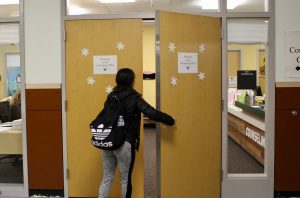 A student is pictured entering the counseling office. The doors must open outward due to safety regulations.
