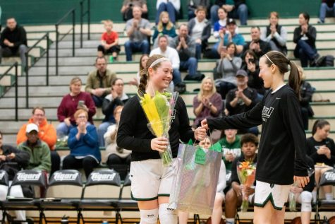 Senior Emily Paulson receives her gift from freshman Hailey Shimojima during senior night against Oregon City. “I am going to miss playing with my teammates and getting to be around them all the time,” Paulson said.
